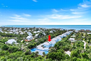 A coastal residential area with a large blue building highlighted by a red arrow, surrounded by lush greenery and a clear view of the ocean. - 2 bedroom accommodation in Sanibel Island (Sanibel Island)