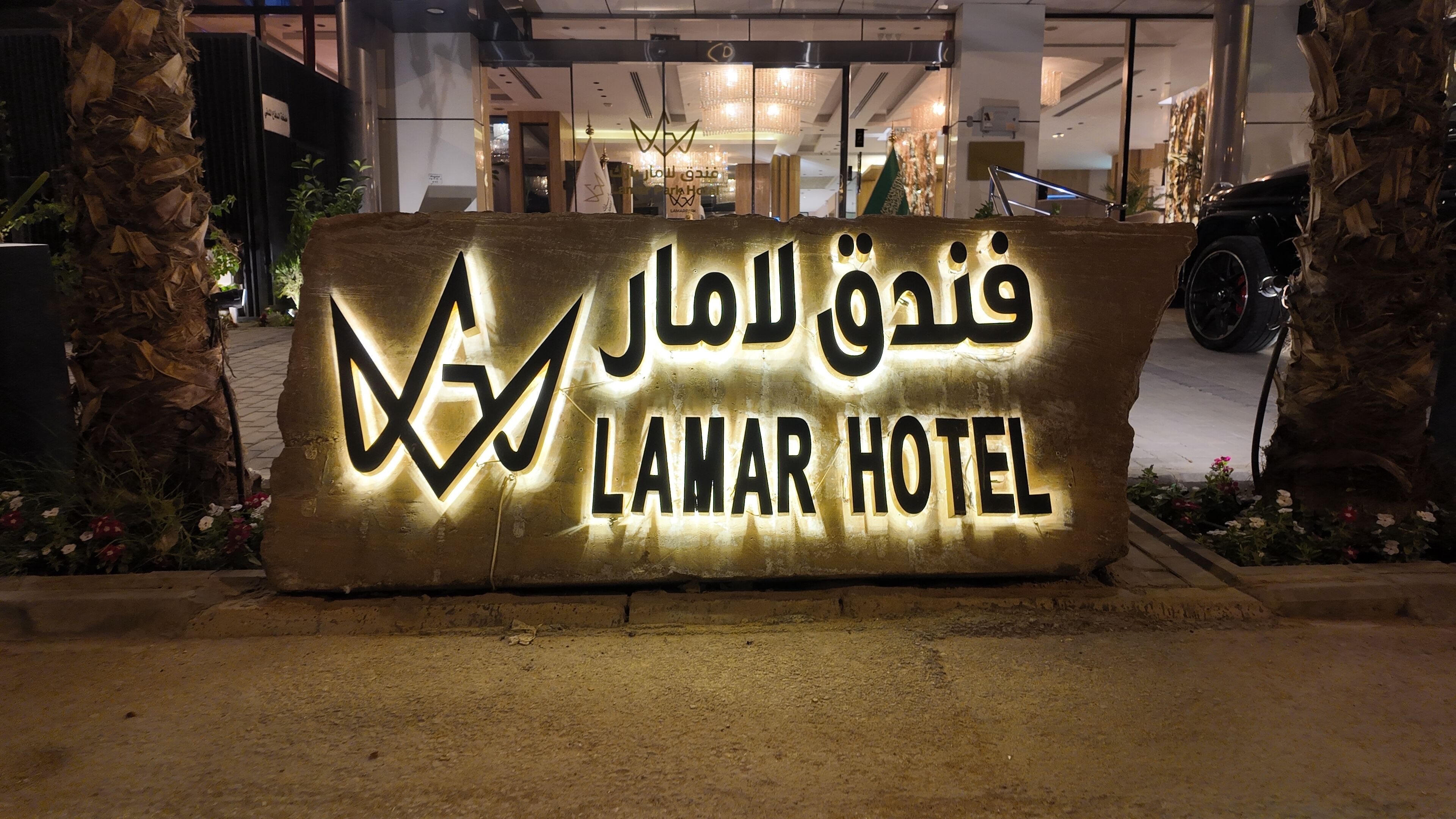 A sign for the Lamar Hotel with illuminated Arabic text and English translation.