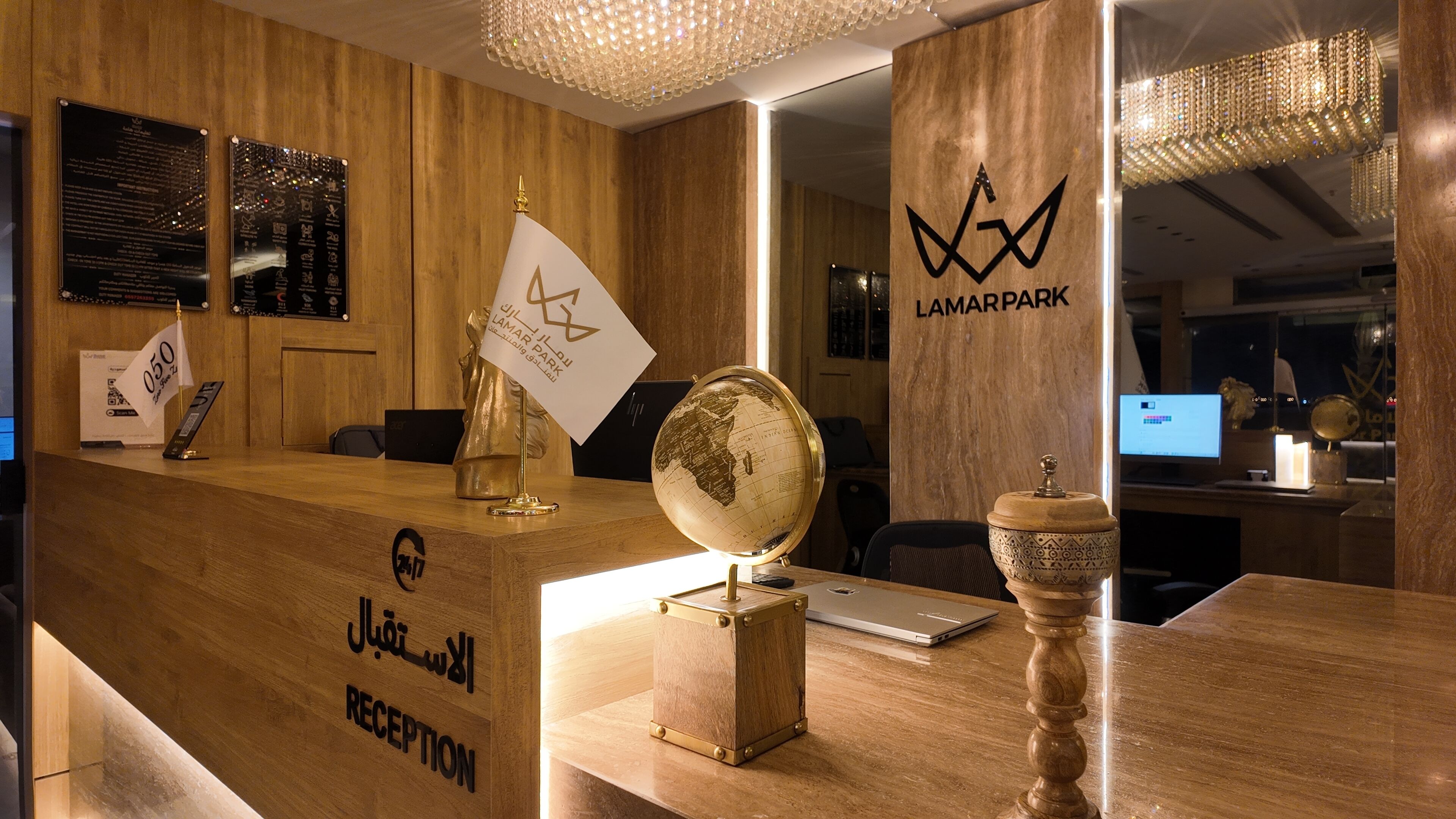 Un mostrador de recepción con detalles de madera, un globo dorado, una bandera y un letrero que dice 'LAMARPARK'.