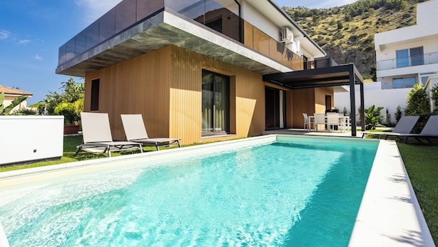 A modern two-story house with a swimming pool, outdoor seating, and a mountainous backdrop. - Luxury Villa Neptune (Palermo)