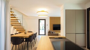 A modern kitchen with a wooden table, chairs, and a built-in oven. - Luxury Villa Neptune (Palermo)