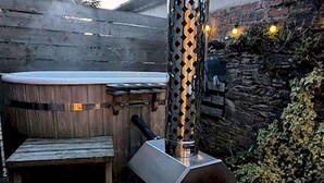 Ein Whirlpool mit einer Holzterrasse und einer Steinwand im Hintergrund.