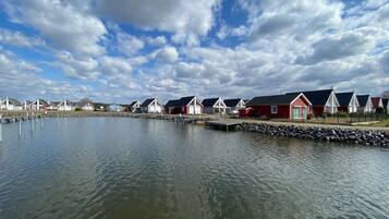 Una hilera de cabañas rojas y blancas junto a un lago tranquilo con un muelle.