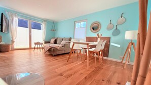 A modern living room with a sofa, dining table, chairs, and a lamp. - Ferienhaus Sanibel mit Kaminofen (Wandlitz)