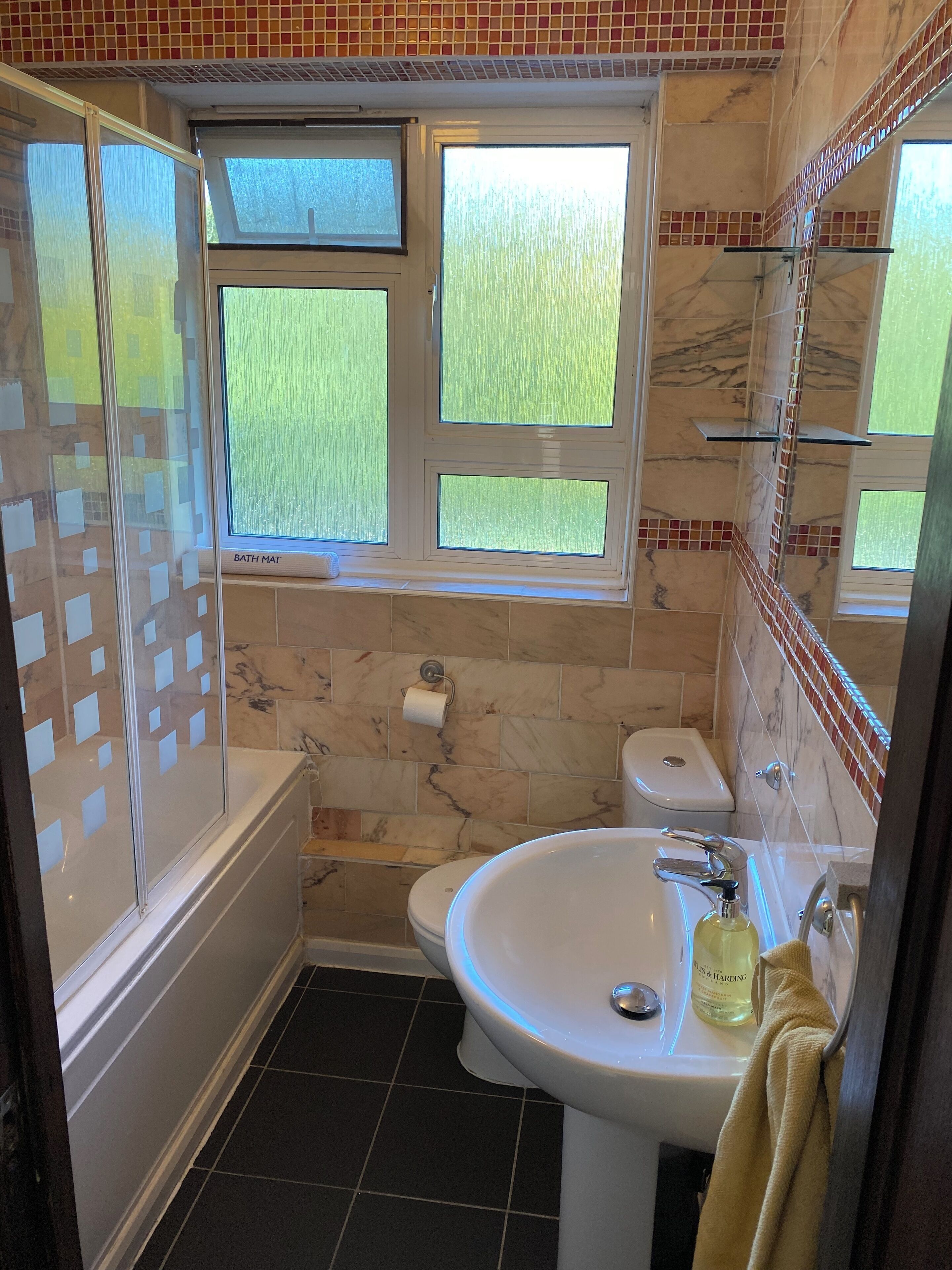 A bathroom with a bathtub, a sink, and a window with a view of greenery.