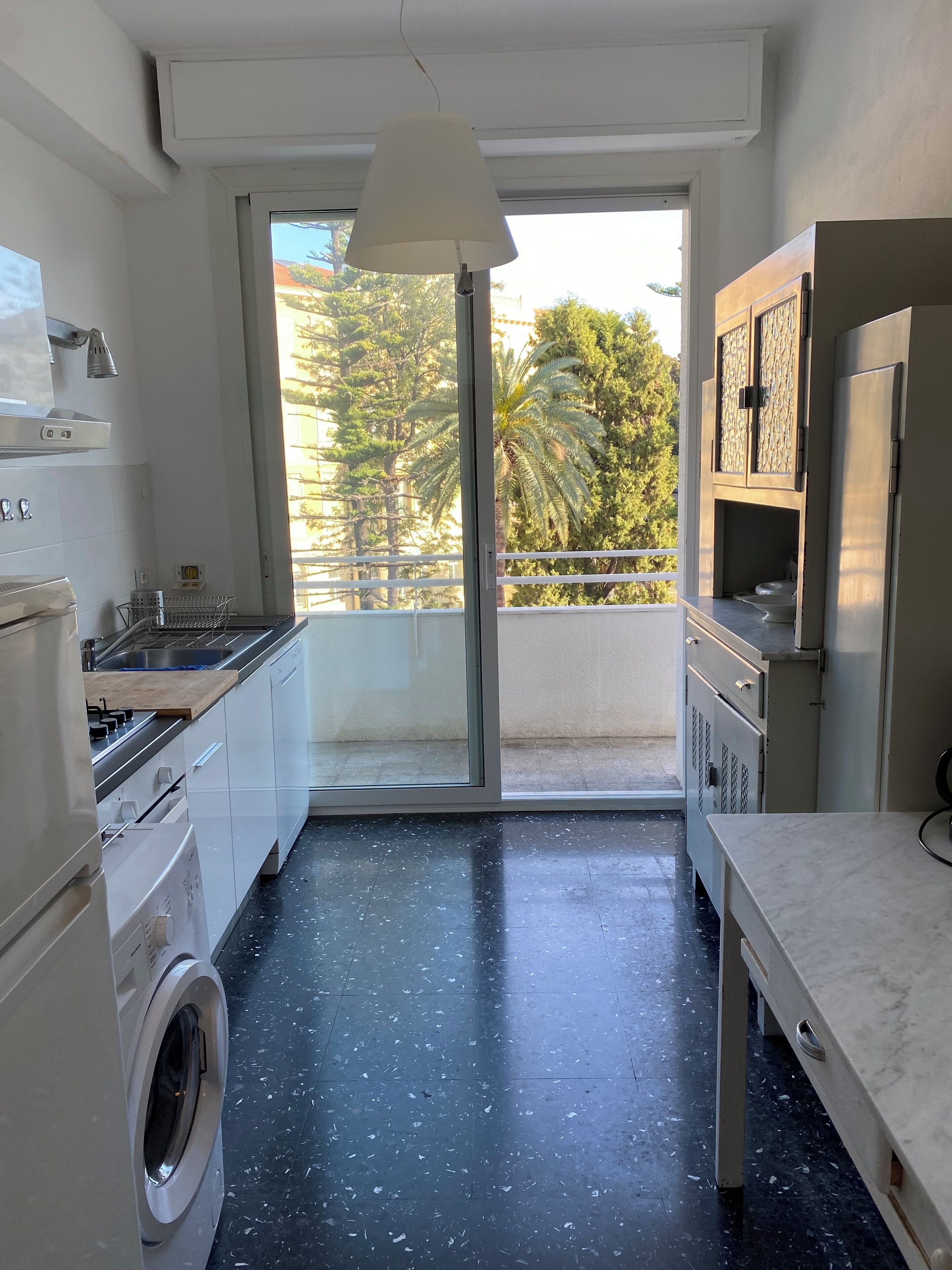 A compact kitchen with a washing machine, a stove, and a sink.