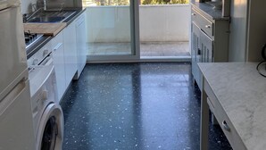 A compact kitchen with a washing machine, a stove, and a sink. - Penthouse near the beach and bike lane (Sanremo)