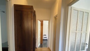 A hallway with wooden flooring, a large wooden wardrobe, and a glass door with frosted glass panels. - Penthouse near the beach and bike lane (Sanremo)