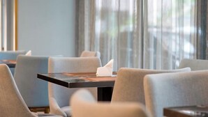 En restaurant med borde og stole, en serviet på et bord, og udsigt gennem vinduet.