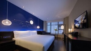 Et moderne hotelværelse med en stor seng, sengeborde, et skrivebord og et fjernsyn.