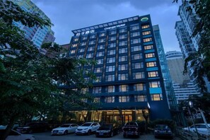 Un hôtel à plusieurs étages, doté d’une façade moderne, d’un parking et d’une entrée bien éclairée.