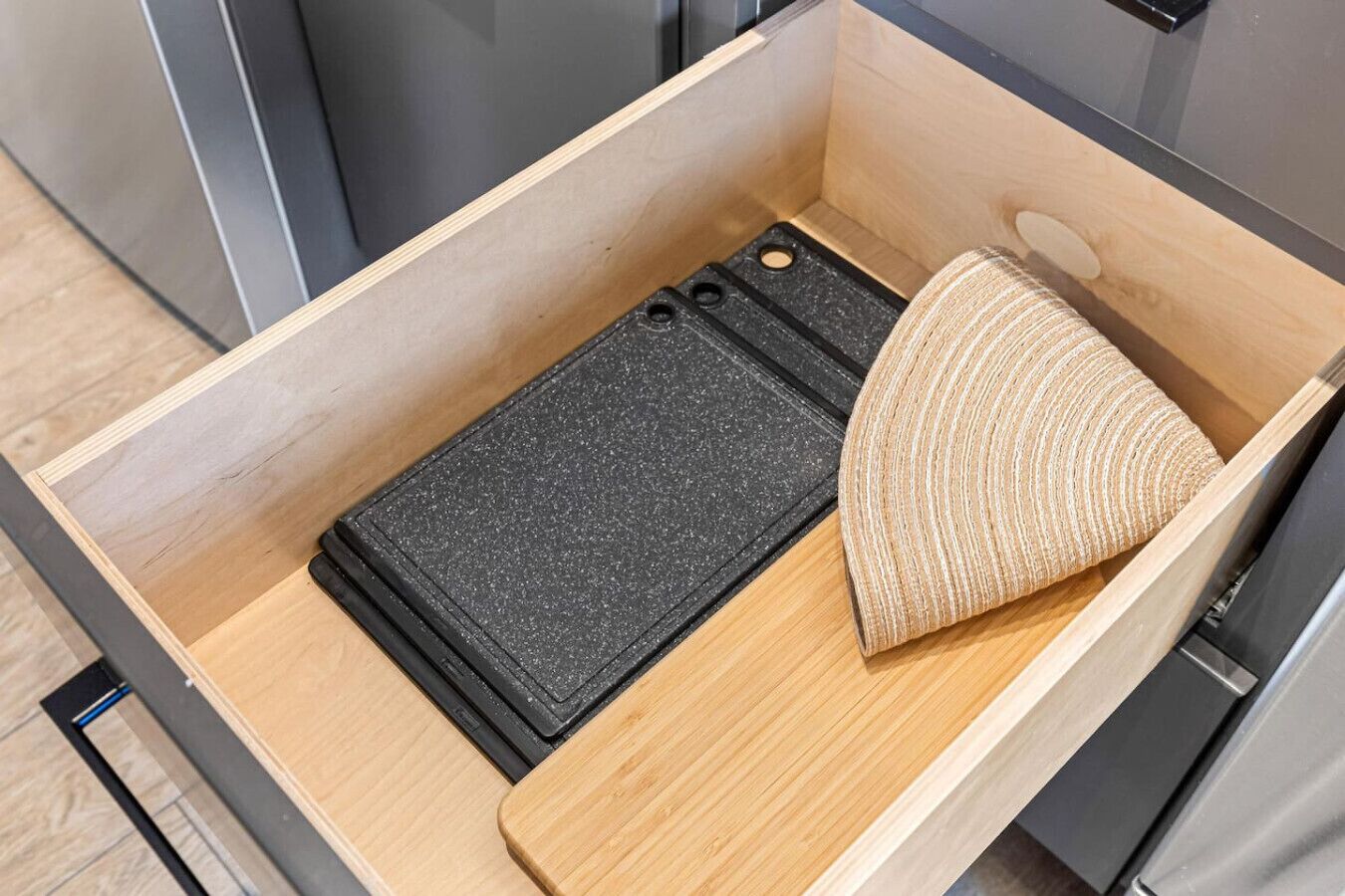 A drawer with a black mat and a woven item.