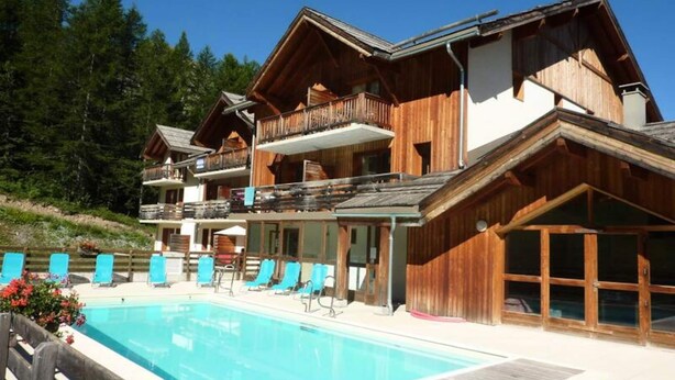 Eine Holzchalet mit Pool, Balkonen und Blick auf den umliegenden Wald.