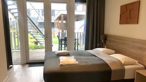 Ein Schlafzimmer mit einem großen Bett, einem Holzkopfende und Blick auf eine Treppe, die zu einem Außenbereich führt.