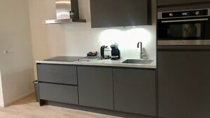 Eine moderne Küche mit einer Edelstahl-Dunstabzugshaube, einem eingebauten Backofen und einer Kaffeemaschine auf der Arbeitsfläche.