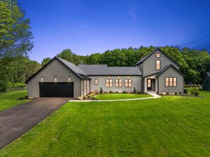 Une maison à deux étages avec un garage, une véranda et une pelouse bien entretenue.