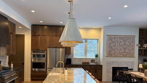 Una cocina moderna con una isla grande, electrodomésticos de acero inoxidable y una lámpara colgante.