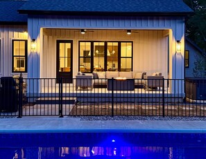 A house with a covered patio, outdoor seating, and a pool. - Lakeshore Woods Escape (Ganges Township)