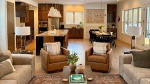 Amplia sala de estar con una mesa de centro, dos sofás y un comedor con una cocina al fondo.