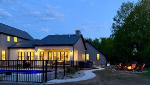 Una casa residencial con piscina, un patio cubierto y un jardín cercado.