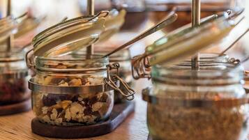 A row of glass jars with metal lids and handles, containing various food items, displayed on a wooden surface.