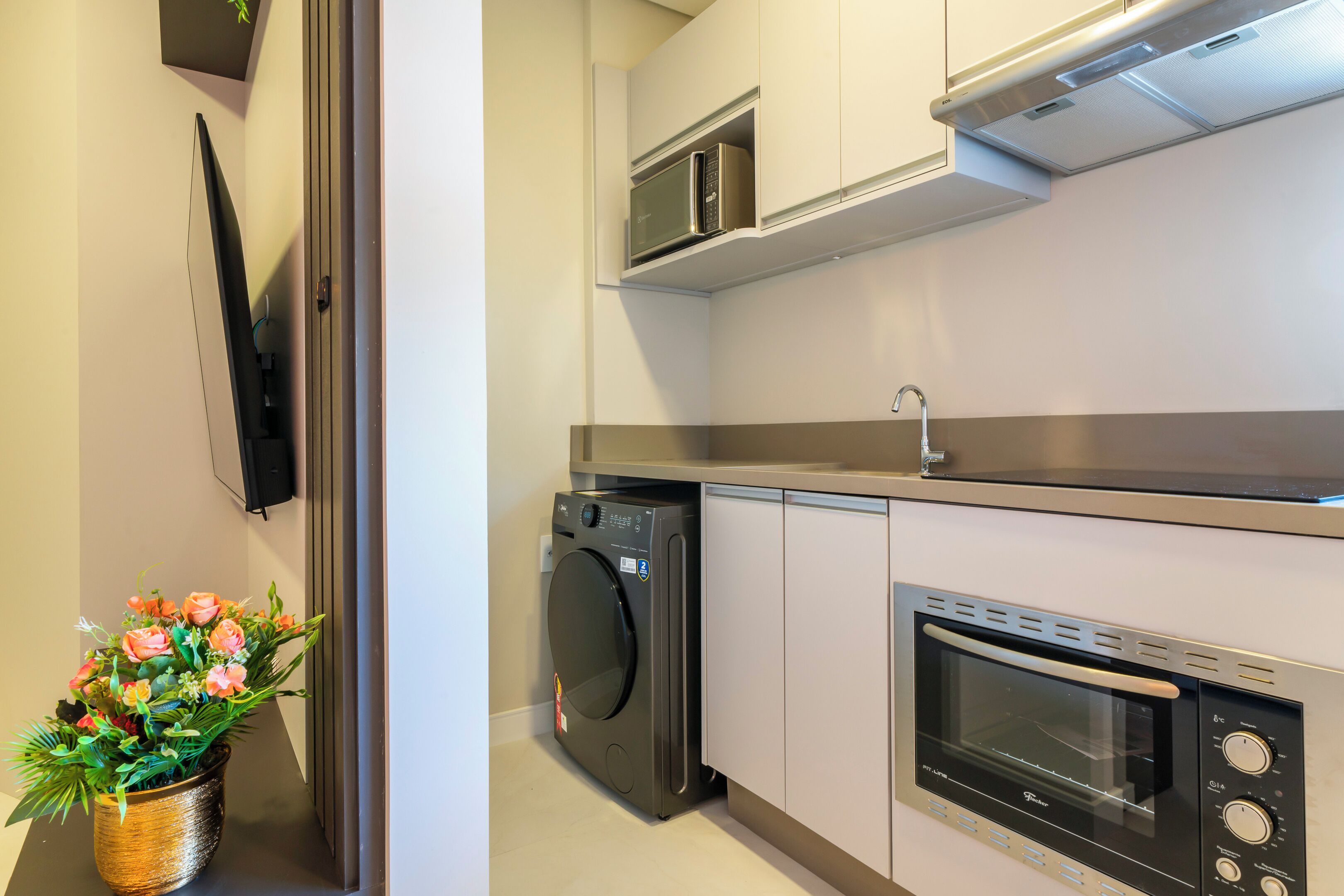 A compact kitchen with a washing machine, microwave, and oven.