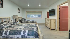 A bedroom with two beds, a dresser, a TV, and a window with a view.