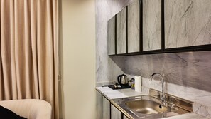 A modern kitchen with a stainless steel sink, marble backsplash, and black cabinets. - Lamar Park for serviced apartments (Riyadh)