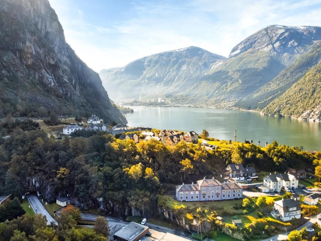 Et bjerglandskab med en sø, en gruppe bygninger og et markant hvidt hus.
