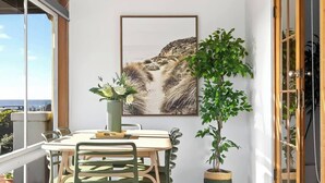 Un comedor con una mesa y sillas, una planta en maceta y un cuadro en la pared.