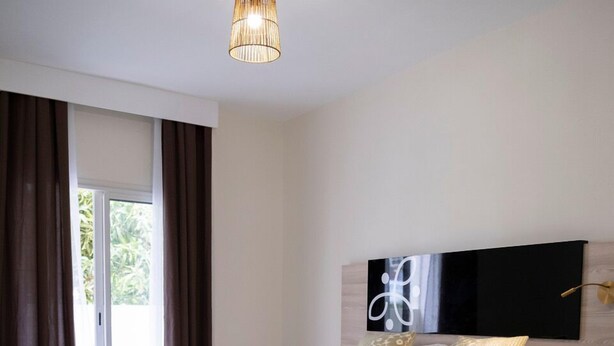 Ein modernes Schlafzimmer mit einem großen Bett, einem Sessel und Blick durch eine Glastür.