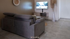 Ein modernes Wohnzimmer mit einem grauen Sofa, einem Flachbildfernseher und Wanddekoration.