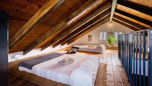 Une chambre mansardée avec un plafond en pente, un lit, un canapé et une petite table.