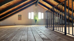 Une chambre mansardée avec un plancher en bois, une rambarde en métal et une plante en pot.