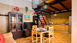 Une cuisine spacieuse avec un coin repas, un escalier et un mur en briques.