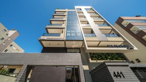 A modern high-rise building with multiple balconies and a prominent 'Sunny' sign. - APTO flat em condomínio com piscina B (Bombinhas)