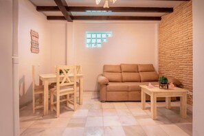 Een gezellige kamer met een bank, een houten tafel en een klein plantje.