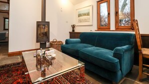 Ein gemütliches Wohnzimmer mit einem blauen Sofa, einem Glastisch und einem Kaminofen.