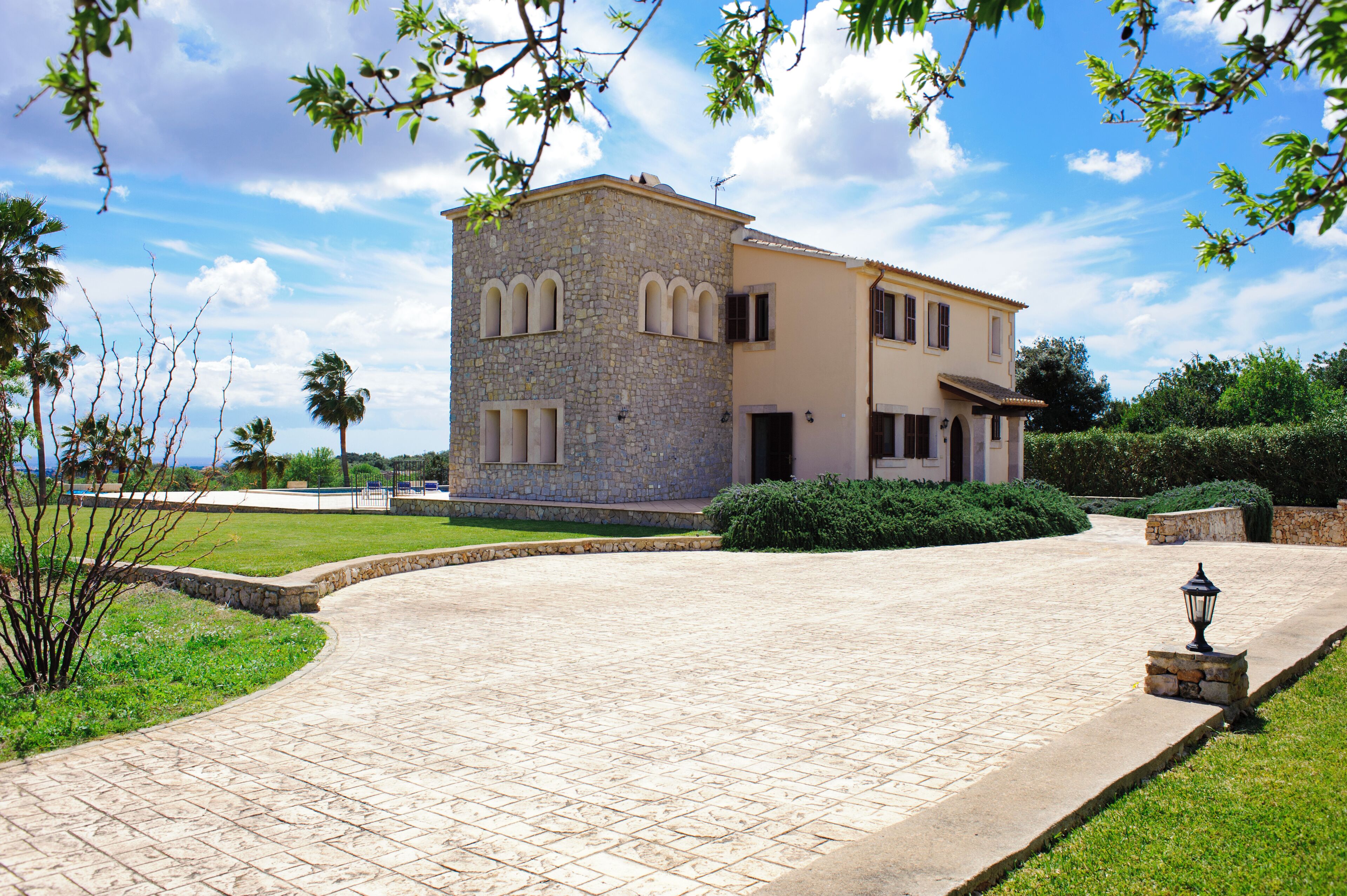 A two-story stone building with a paved driveway and a well-maintained lawn.