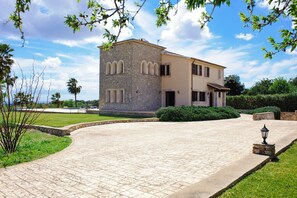 Un edificio in pietra a due piani con vialetto lastricato e prato curato.