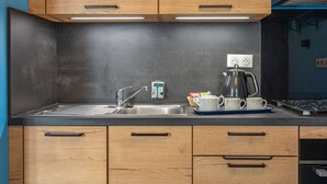 A modern kitchen with wooden cabinets, a stainless steel sink, and a kettle on the countertop. - Furnished Apartment in Townhouse, City Center Location (Jonzac)