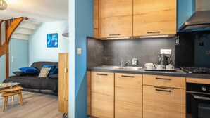 A modern kitchen with wooden cabinets, a black stove, and a sink. - Furnished Apartment in Townhouse, City Center Location (Jonzac)