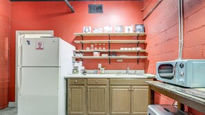 A compact kitchen with a white refrigerator, wooden cabinets, and a microwave on a counter. - Cozy Single at The Strand (Waynesville)