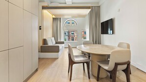 Un comedor moderno con una mesa redonda y sillas, un sofá y un televisor montado en la pared.