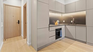 Una cocina moderna con gabinetes grises, un horno empotrado y un lavamanos de acero inoxidable.