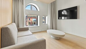 Una sala de estar moderna con un sofá, una mesa de centro redonda y un televisor de pantalla plana montado en la pared.