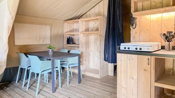 A compact kitchen with a dining area, wooden walls, and a ceiling tent. - Safari Tent Blossom Lodge (Kesteren)