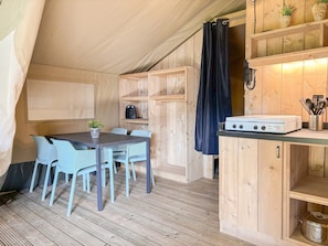 A compact kitchen with a dining area, wooden walls, and a ceiling tent. - Safari Tent Blossom Lodge (Kesteren)