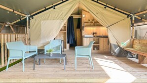A tent with a kitchen area, wooden flooring, and seating arrangements. - Safari Tent Blossom Lodge (Kesteren)