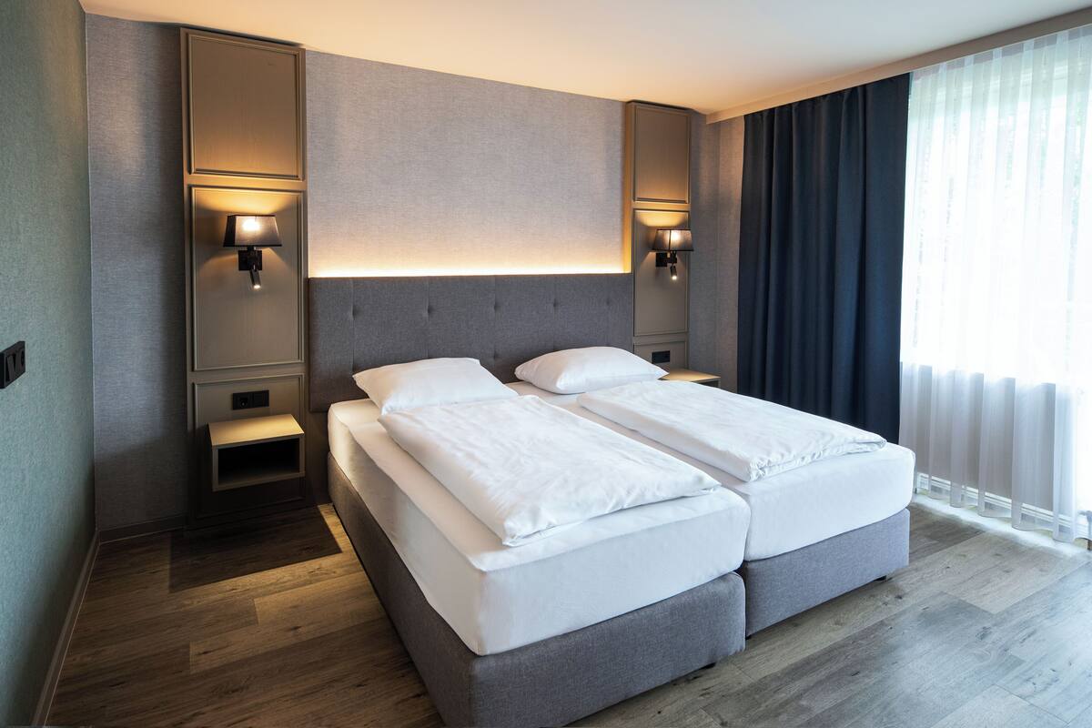 Una habitación de hotel moderna con una cama doble, dos mesitas de noche y lámparas de pared.